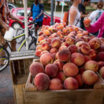 Farmers market peaches and biker walking by